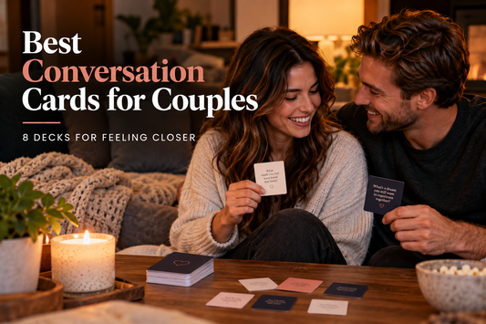 Smiling couple on a couch holding conversation cards, with the title Best Conversation Cards for Couples: 8 Decks for Feeling Closer