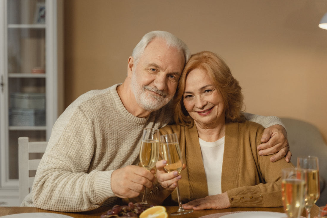 Smiling older couple toasting with champagne at home