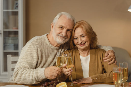Smiling older couple toasting with champagne at home