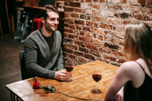 Couple talking over glasses of red wine at a cozy restaurant table