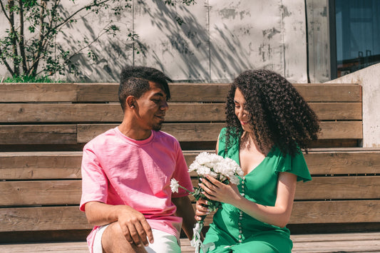 Man giving a woman a bouquet of white flowers on sunny wooden steps